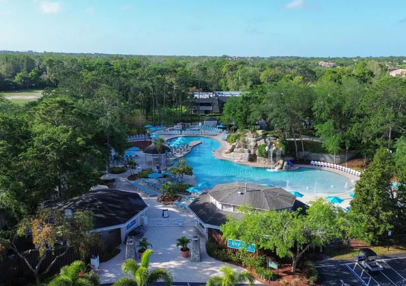 Vue aérienne d'un complexe aquatique avec une piscine sinueuse et des bâtiments environnants.