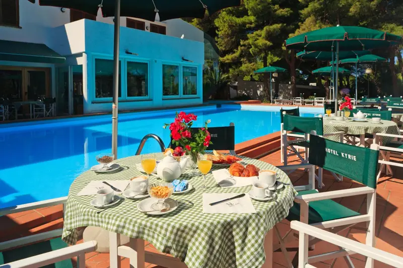 Une table est dressée au bord d'une piscine avec un petit-déjeuner.