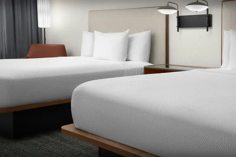 Deux lits simples avec oreillers blancs dans une chambre d'hôtel.