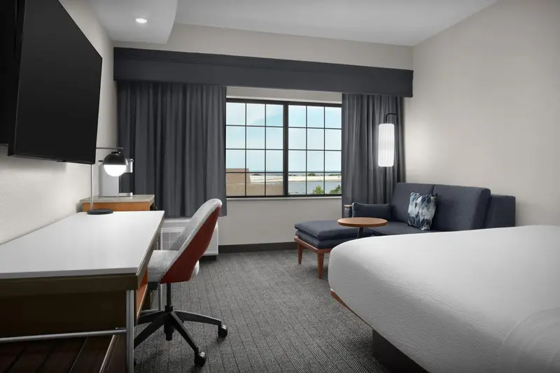 Une chambre d'hôtel lumineuse avec un bureau, un coin salon et une vue sur l'extérieur.