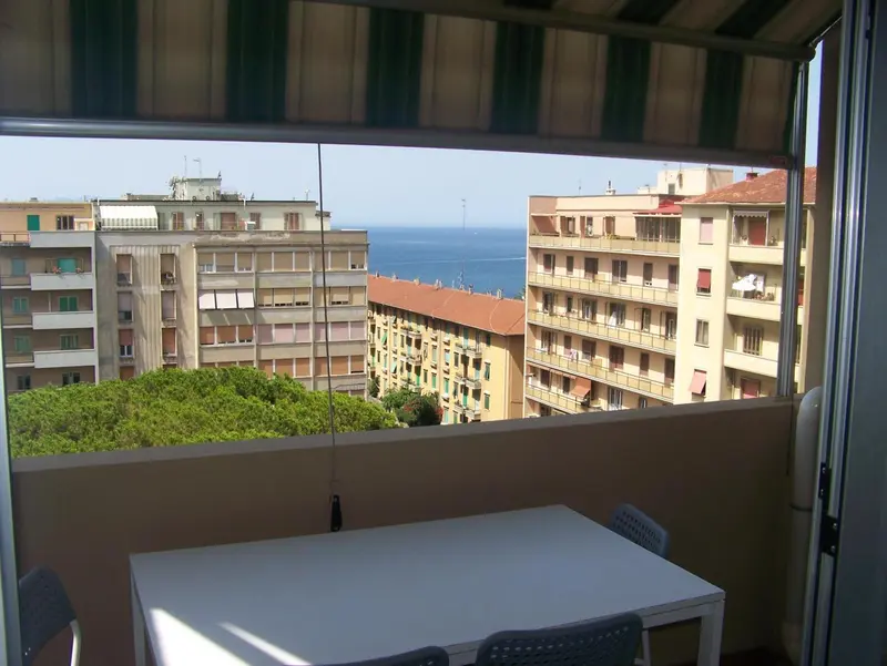 Vue sur la ville et la mer depuis un balcon avec une table.