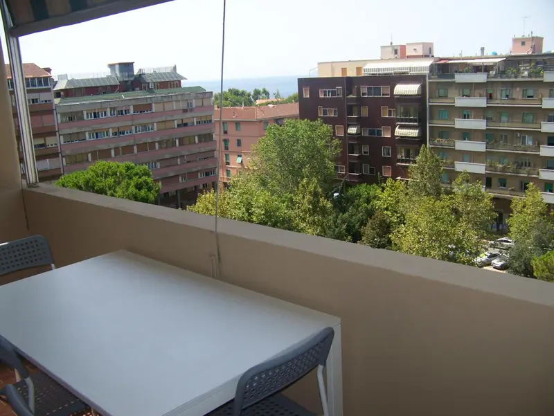 Une table et des chaises sur un balcon avec vue sur la ville et la mer.