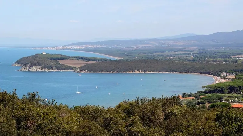 Vue panoramique sur une côte rocheuse et une plage de sable fin.