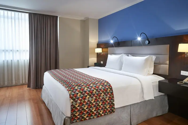 Une chambre d'hôtel avec un grand lit recouvert d'une courtepointe colorée.