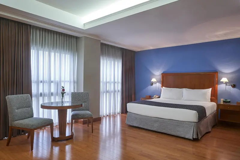 Une chambre d'hôtel lumineuse avec un lit double et un coin salon.