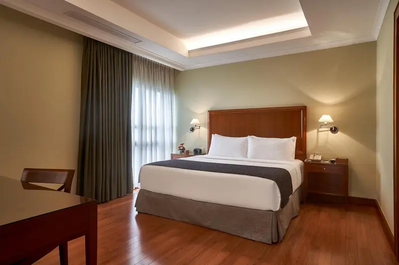 Une chambre lumineuse avec un grand lit et des rideaux verts.