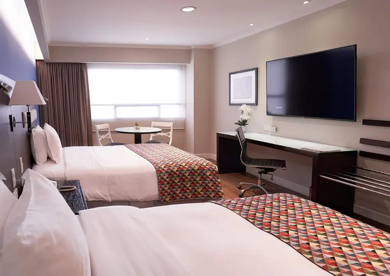 Une chambre d'hôtel lumineuse avec deux lits et un espace de travail.