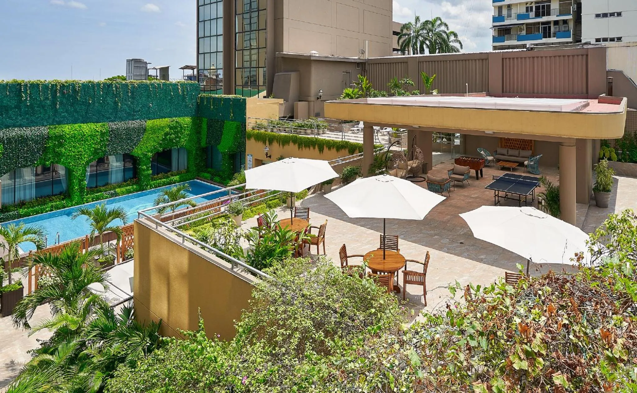Terrasse aménagée avec tables, parasols et mobilier de détente près d'une piscine.