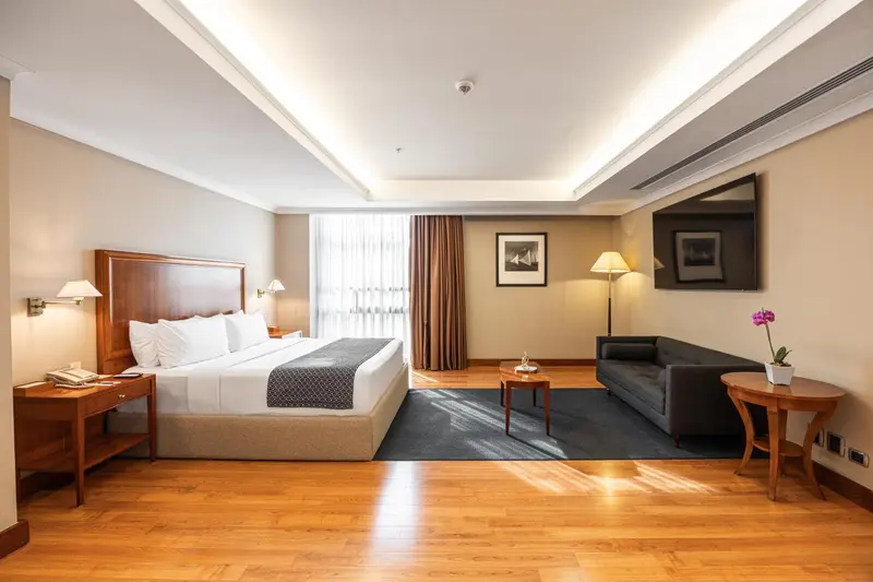 Une chambre lumineuse avec un grand lit et un coin salon.