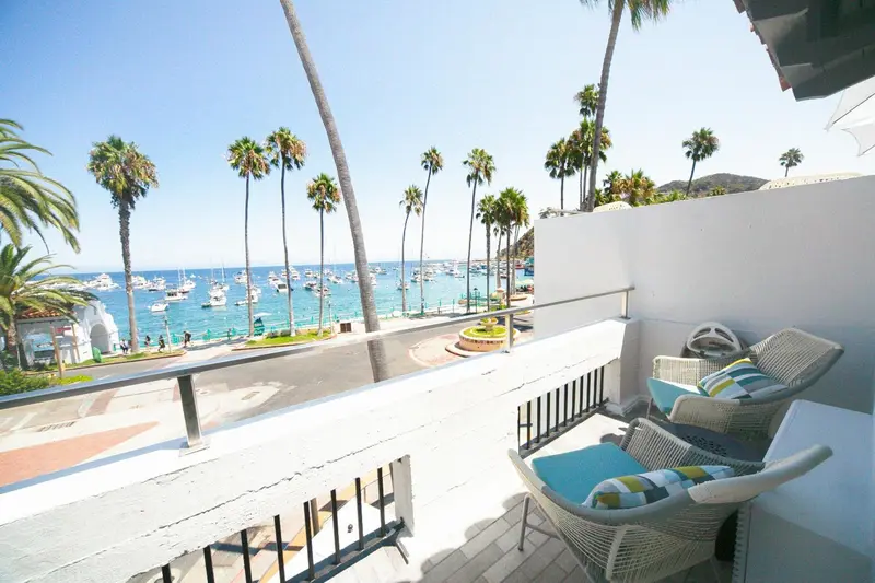 Terrasse avec mobilier d'extérieur donnant sur une vue de la mer et des bateaux.