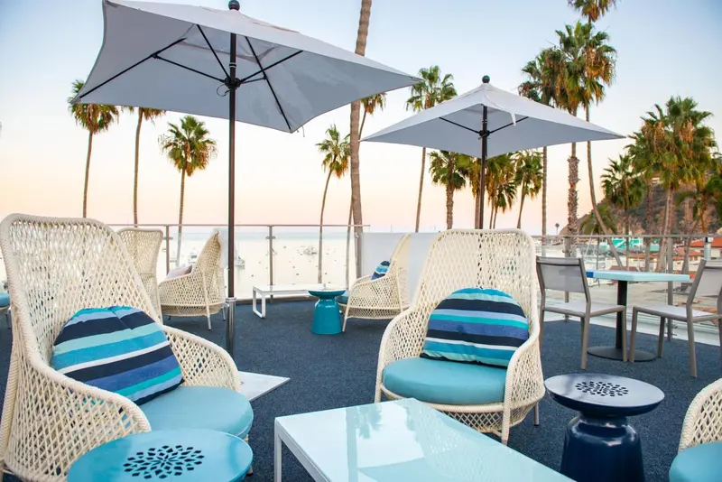 Terrasse aménagée avec des fauteuils et des tables basses face à la mer.