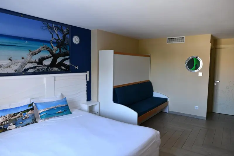 Une chambre lumineuse avec un grand lit et un canapé intégré.