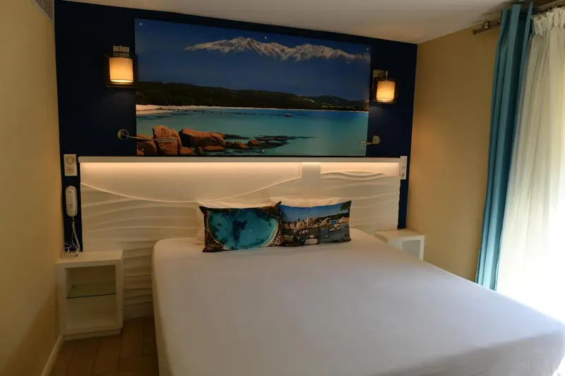 Une chambre lumineuse avec un grand lit et des tableaux décoratifs.
