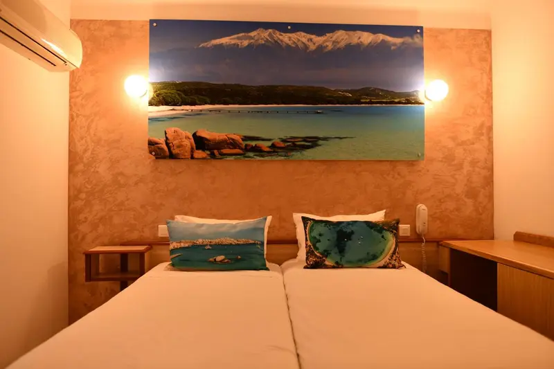 Une chambre lumineuse avec un grand tableau représentant un paysage marin.