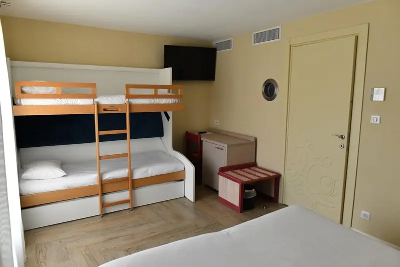 Une chambre avec des lits superposés et un téléviseur mural.
