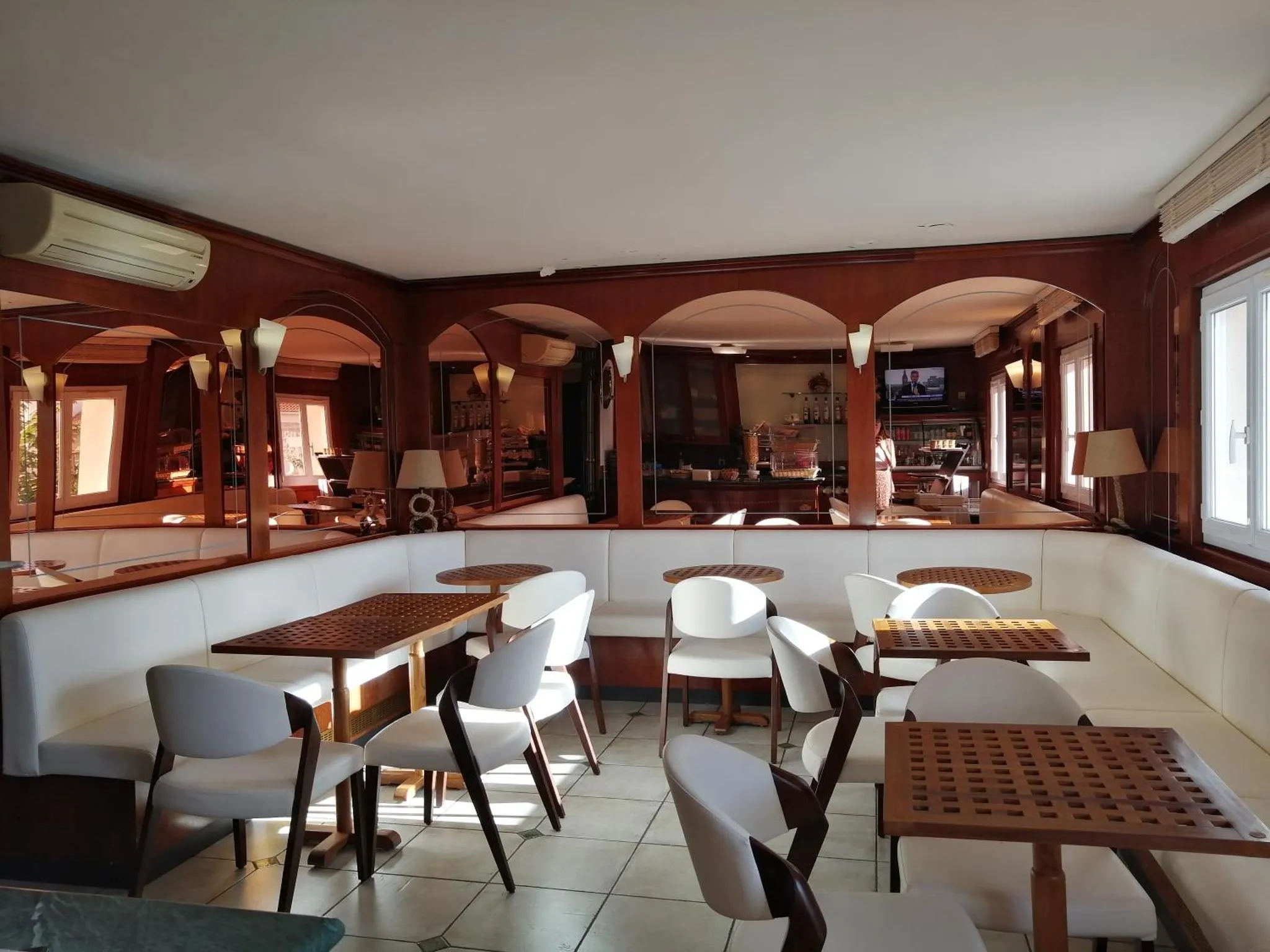 Une salle lumineuse avec des tables et des chaises disposées devant de grandes fenêtres.