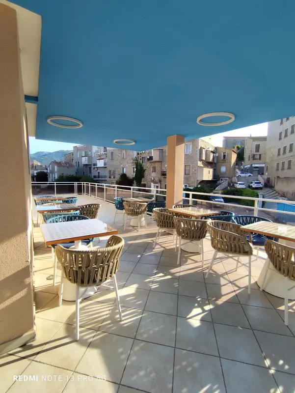 Terrasse ombragée avec tables et chaises en rotin.