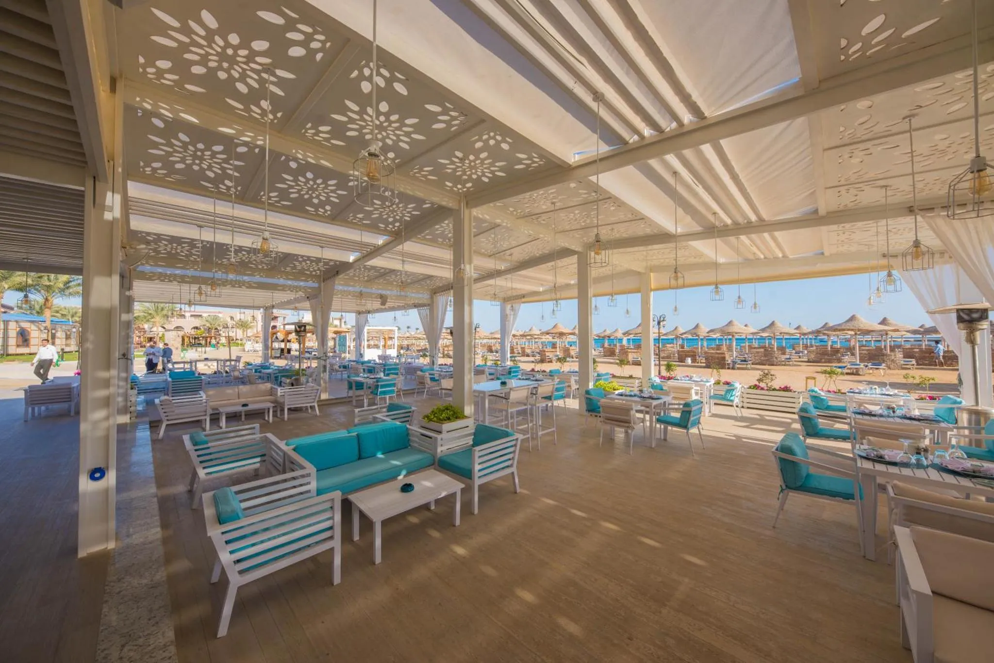Espace de restauration extérieur avec mobilier clair et vue sur la mer.