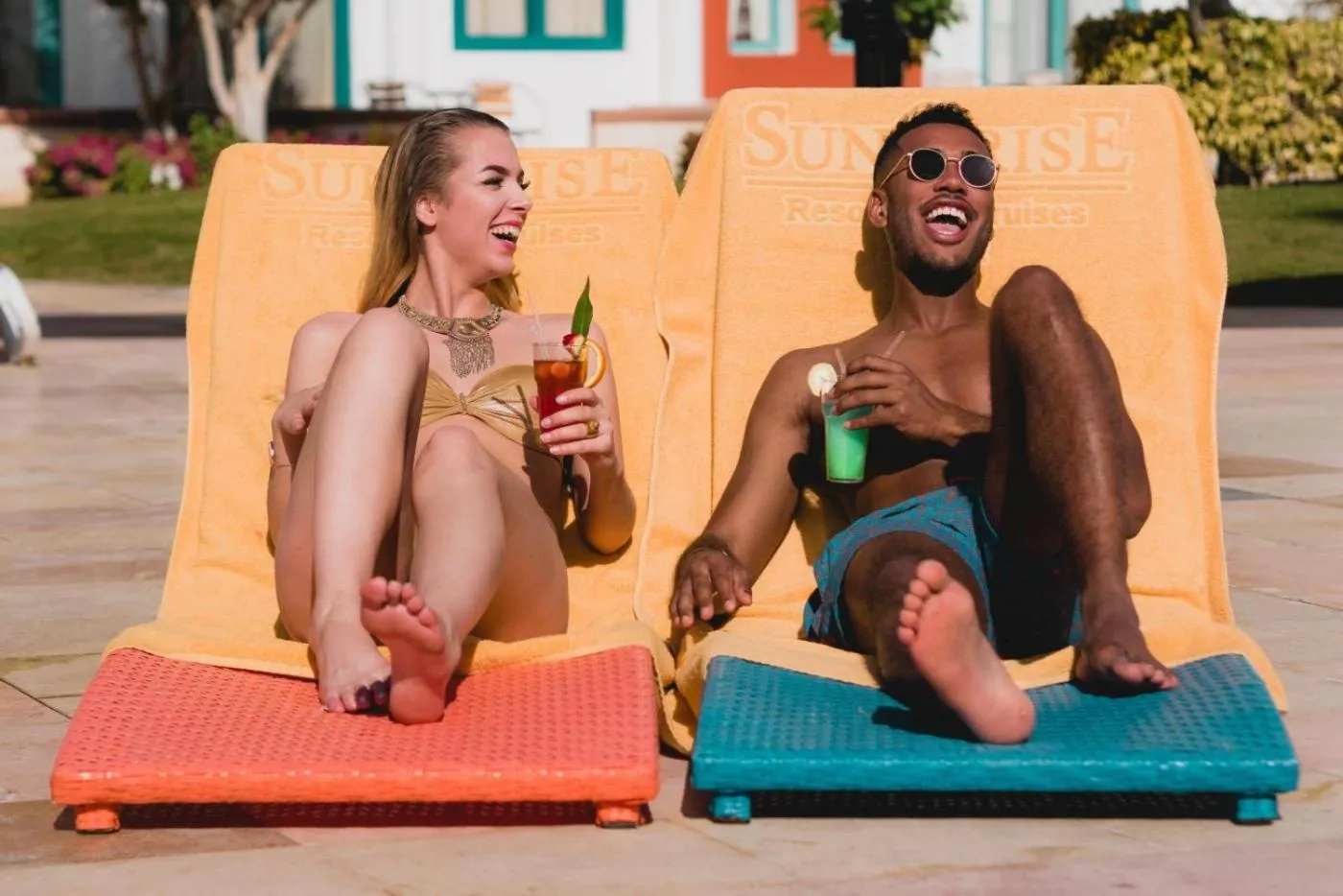 Deux personnes sourient en se relaxant sur des transats colorés.