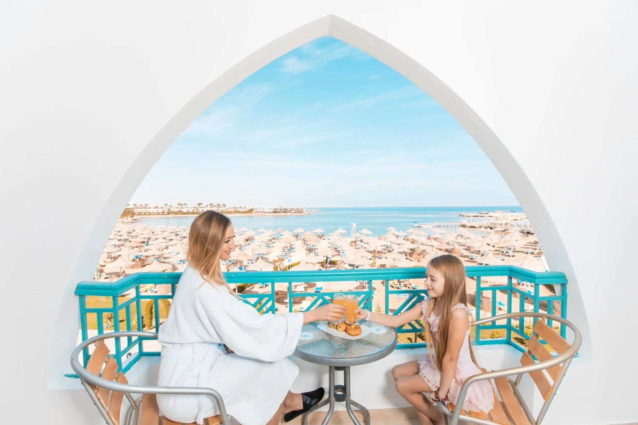 Deux femmes prennent le petit-déjeuner sur un balcon avec vue sur la mer et la plage.