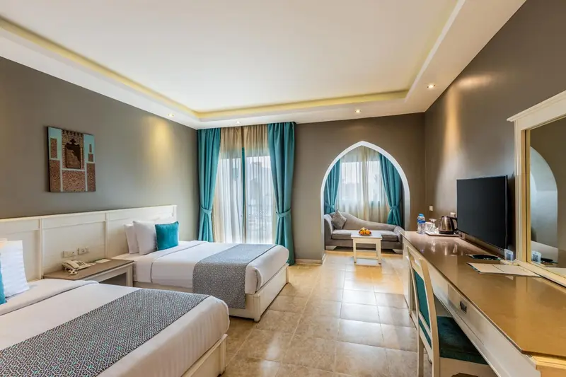 Chambre lumineuse avec deux lits et un coin salon.