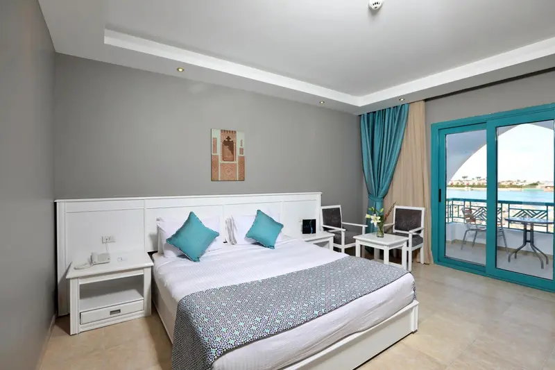 Chambre lumineuse avec un grand lit et une vue sur la mer.