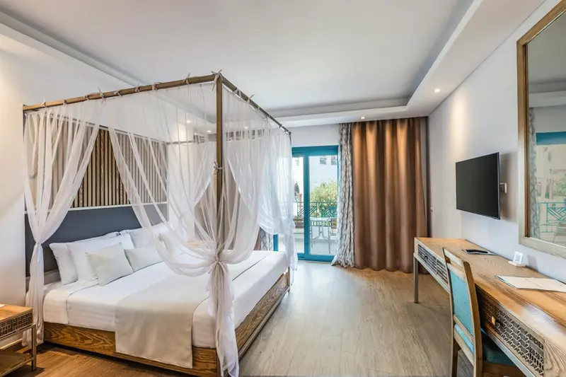 Une chambre lumineuse avec un lit à baldaquin et un bureau.