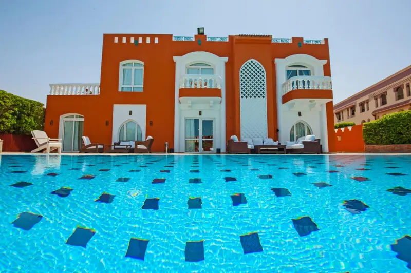 Façade d'un bâtiment orange avec une piscine au premier plan.