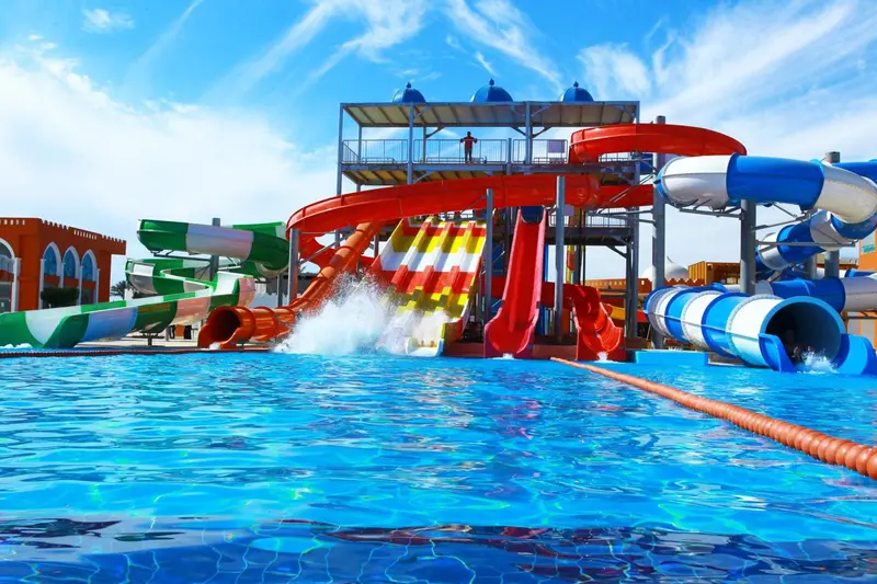 Un parc aquatique avec des toboggans colorés et une piscine ensoleillée.