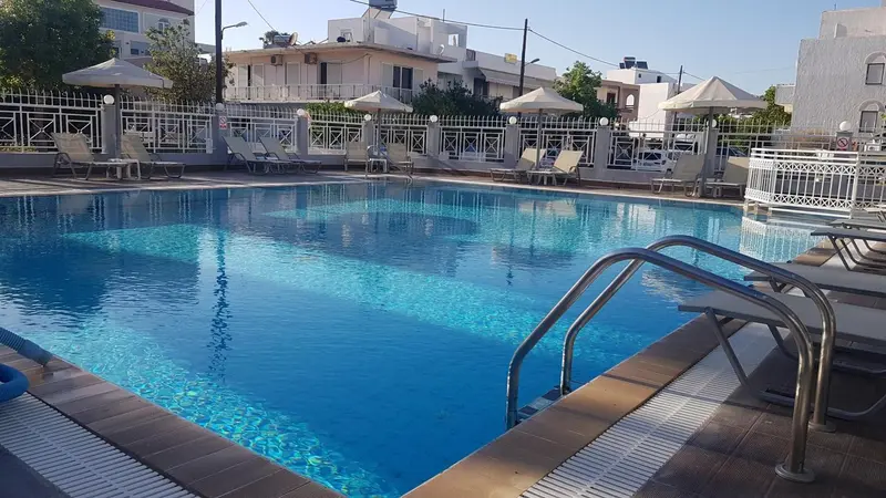 Une piscine bleue entourée de chaises longues et de parasols.
