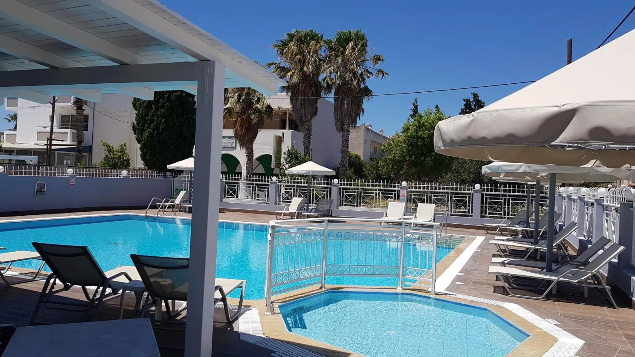 Transats et parasols bordent une piscine turquoise dans un espace extérieur ensoleillé.