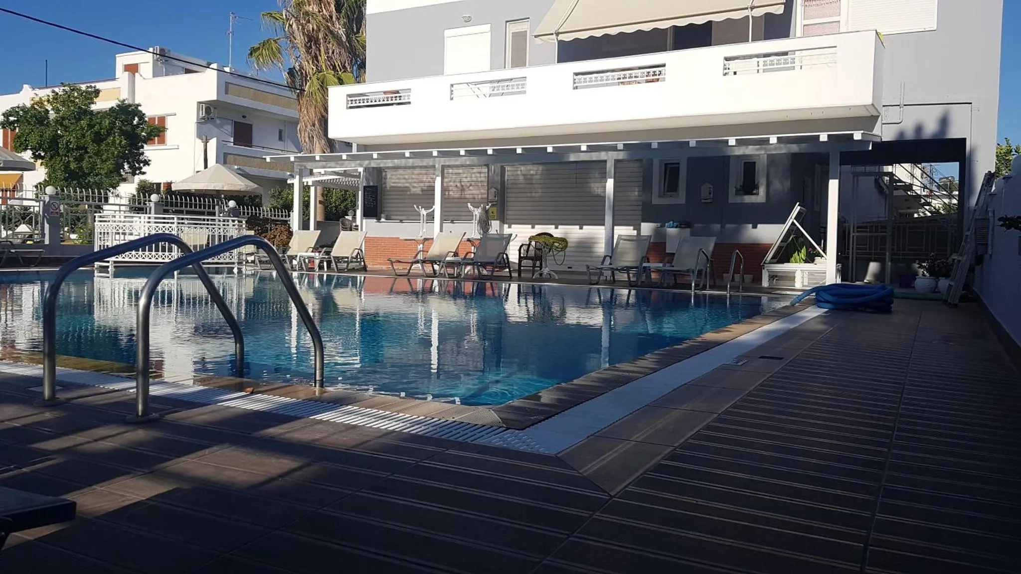 Une piscine rectangulaire avec des transats et des parasols sur une terrasse carree.