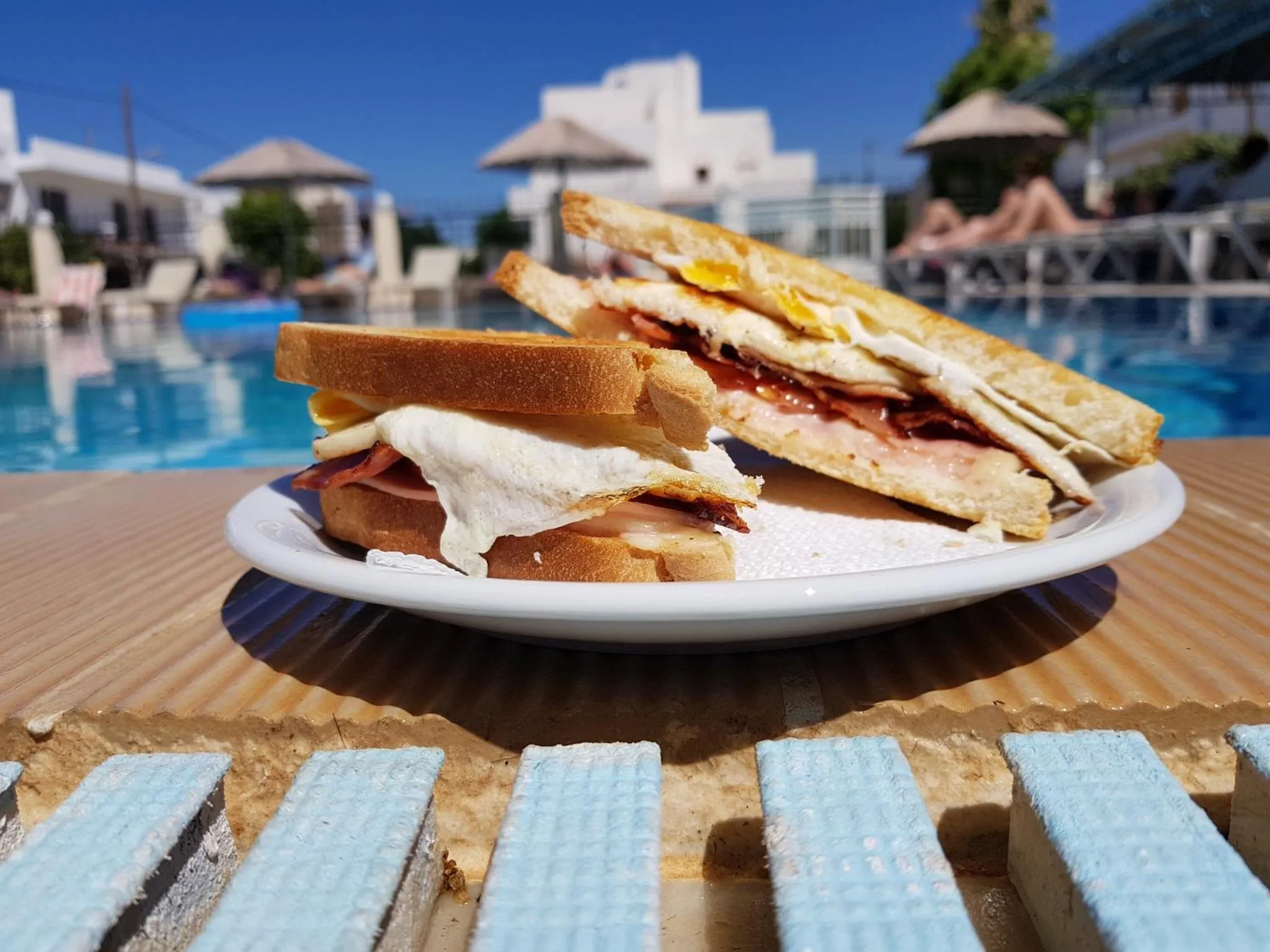 Un sandwich généreux est présenté sur une table près d'une piscine.