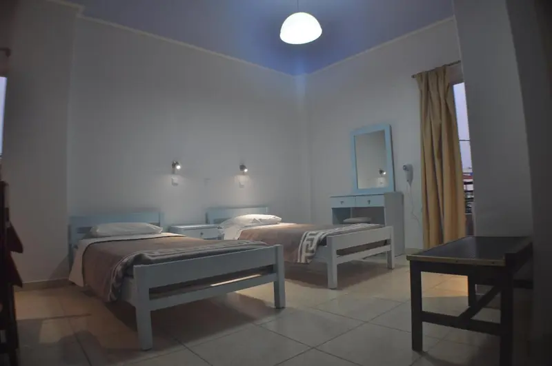 Une chambre lumineuse avec deux lits simples et un miroir.