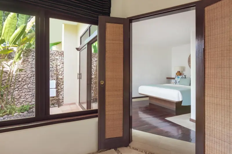 Une chambre lumineuse s'ouvre sur un espace extérieur verdoyant.