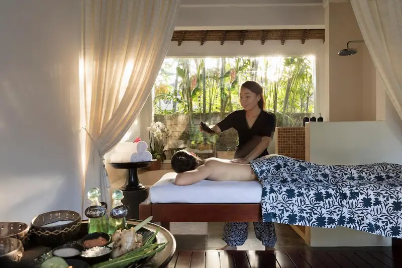 Une femme reçoit un massage dans une pièce lumineuse et décorée.