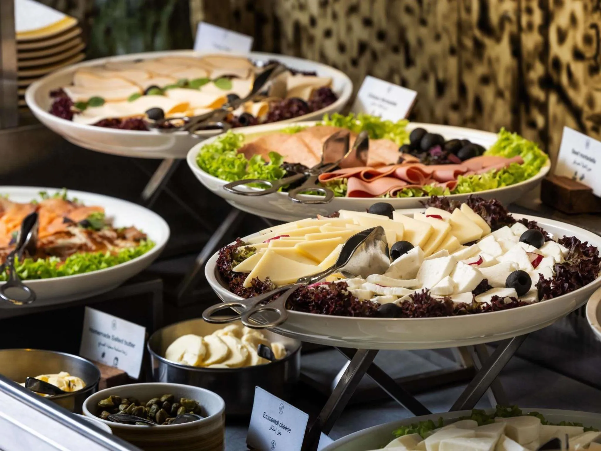 Présentation de salades, charcuteries et fromages sur un buffet.