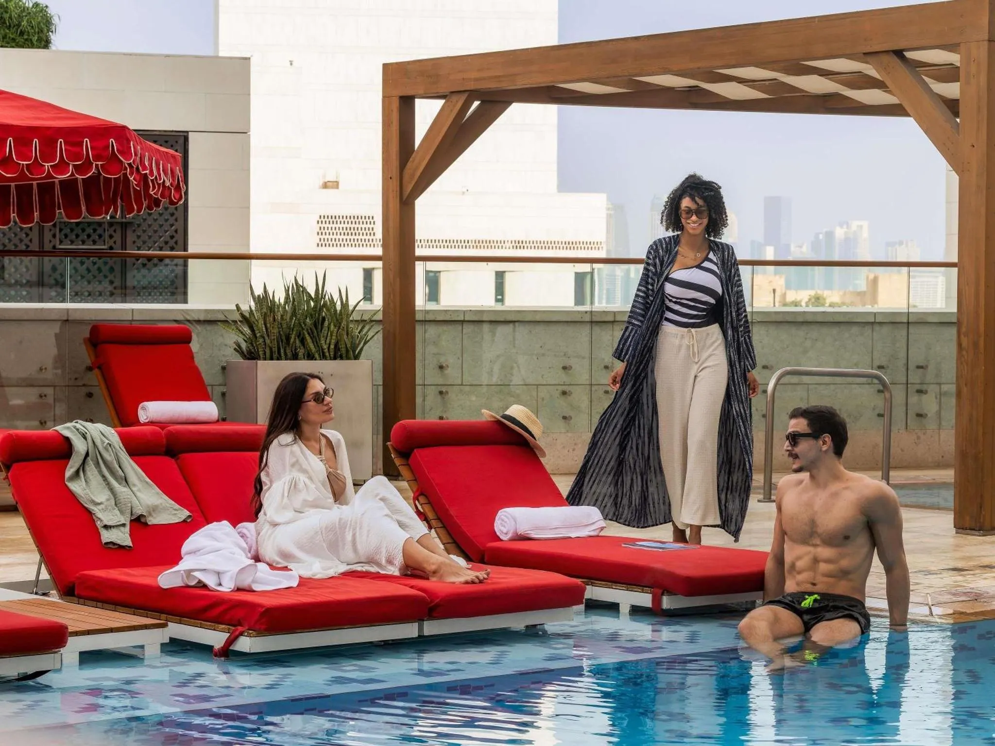 Des personnes se détendent au bord d'une piscine sur une terrasse ensoleillée.