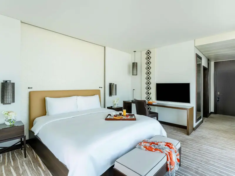 Chambre lumineuse avec un grand lit et un espace bureau.
