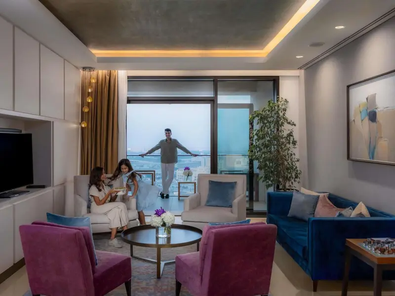 Un salon lumineux s'ouvre sur une vue urbaine par de grandes baies vitrées.