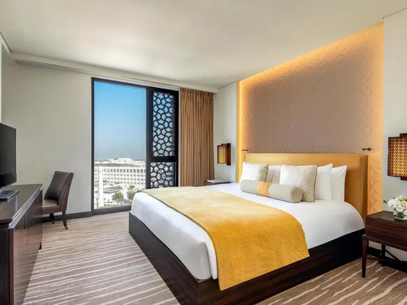 Chambre lumineuse avec un grand lit et une vue sur la ville.
