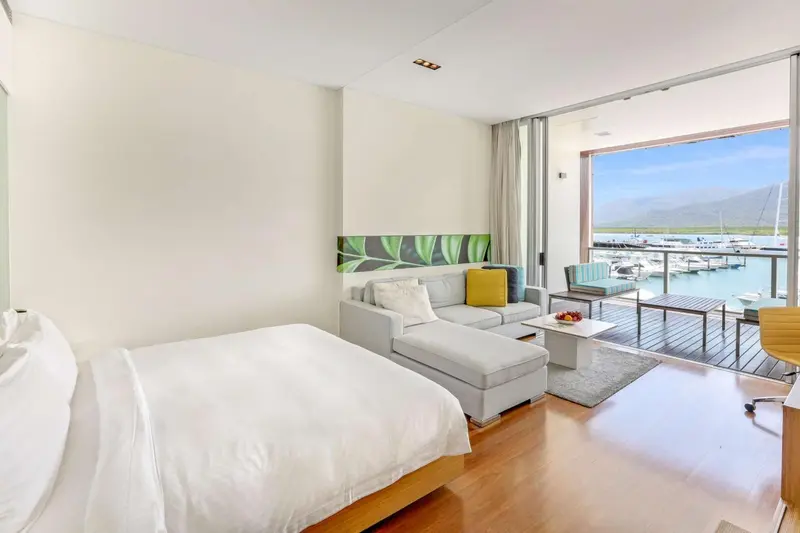 Une chambre lumineuse avec un canapé et un accès à une terrasse donnant sur un port de plaisance.