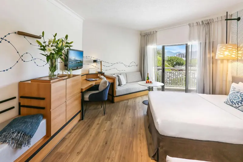 Une chambre lumineuse avec un lit, un coin salon et un balcon.