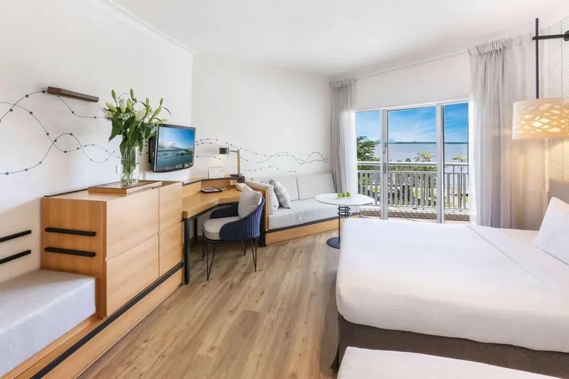 Une chambre lumineuse avec un coin salon et vue sur la mer.