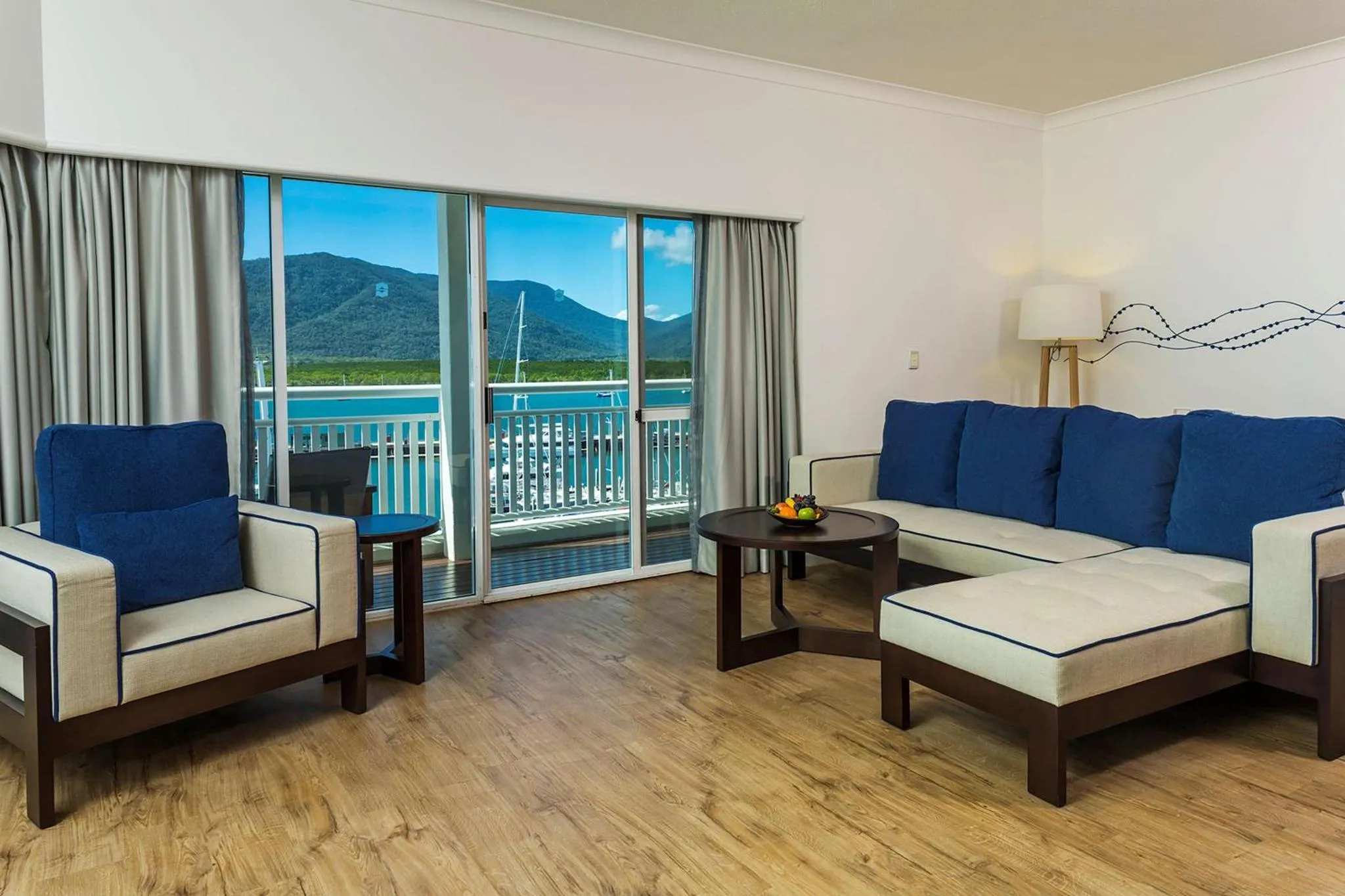 Espace de détente lumineux avec canapés bleus et vue sur la mer.