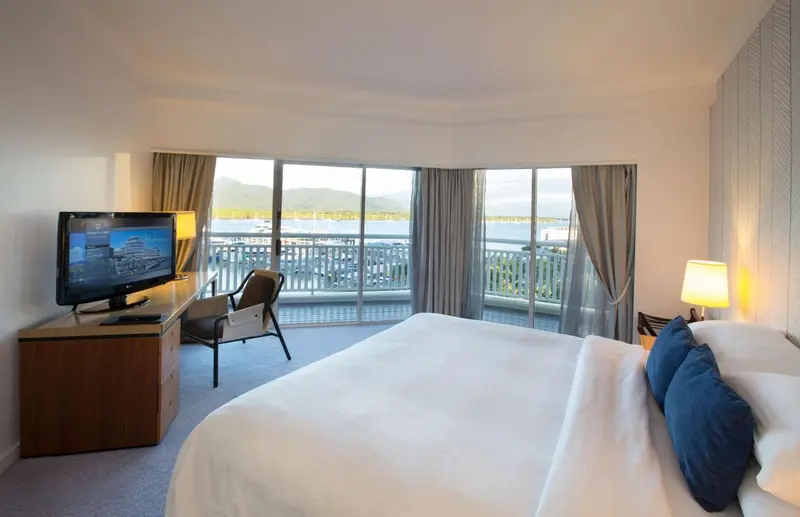 Chambre lumineuse avec un grand lit et une vue sur la mer.