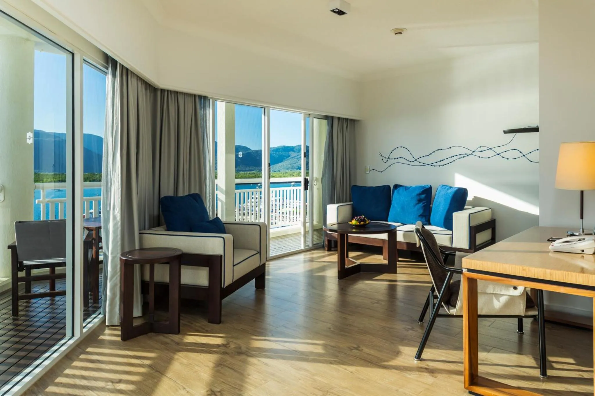 Espace de détente lumineux avec canapés bleus et vue sur la mer.
