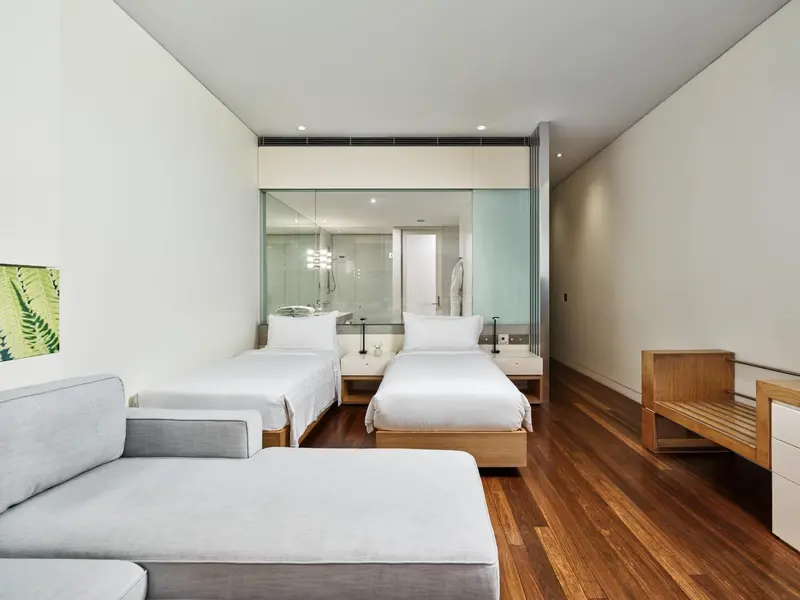 Une chambre lumineuse avec deux lits simples et un canapé.