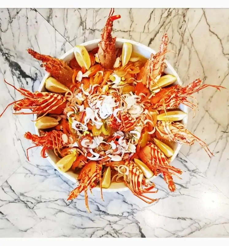 Présentation artistique de langoustes et de légumes dans un saladier.