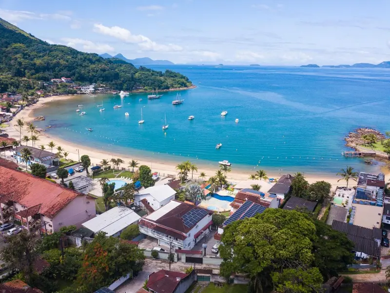 Vue aérienne d'une plage bordée de bâtiments et de végétation luxuriante.